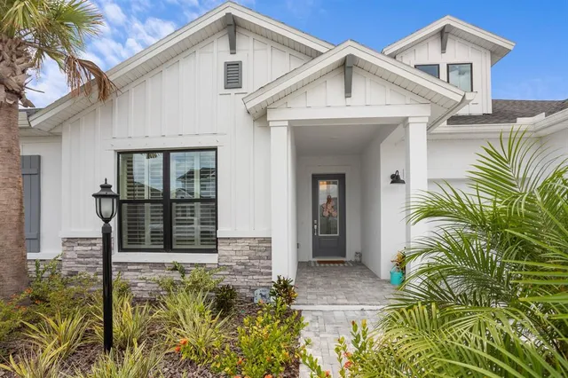 a view of a white house next to a yard with potted plants
