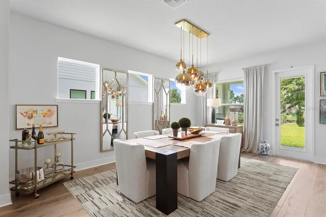 a dining room with wooden floor a chandelier a glass table and windows