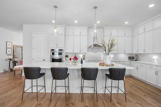 a kitchen with stainless steel appliances kitchen island granite countertop a dining table chairs and white cabinets