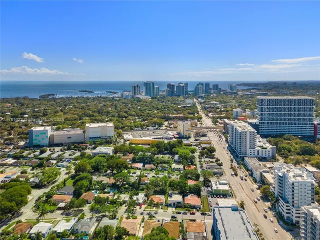 an aerial view of a city with lots of residential buildings ocean and mountain in back