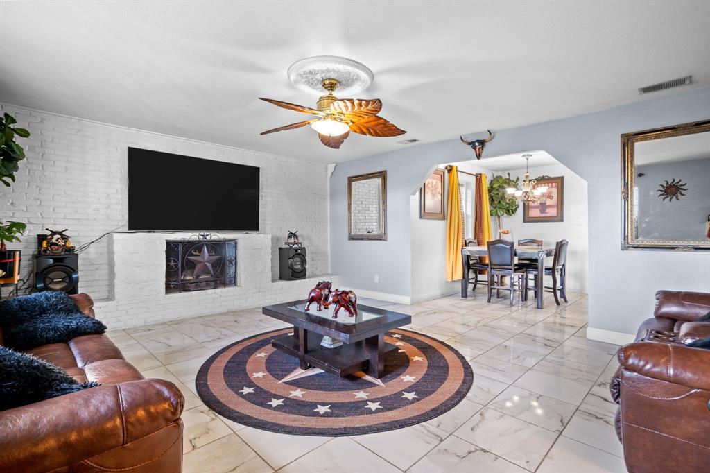 2133 Pleasant Drive Dallas, TX 75227 - Photo 8 of 40 Living room featuring light marble finish flooring, ceiling fan, a fireplace, a chandelier, and brick wall