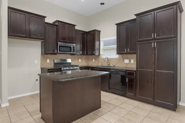 a kitchen with stainless steel appliances granite countertop a stove a sink and a microwave