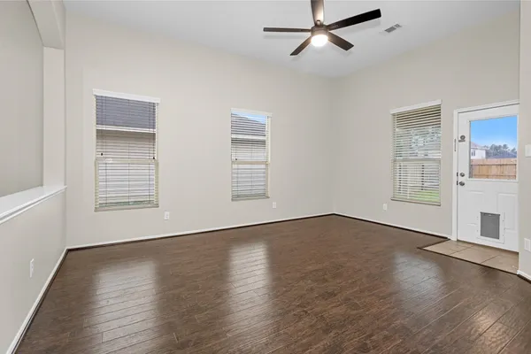 an empty room with wooden floor fan and windows