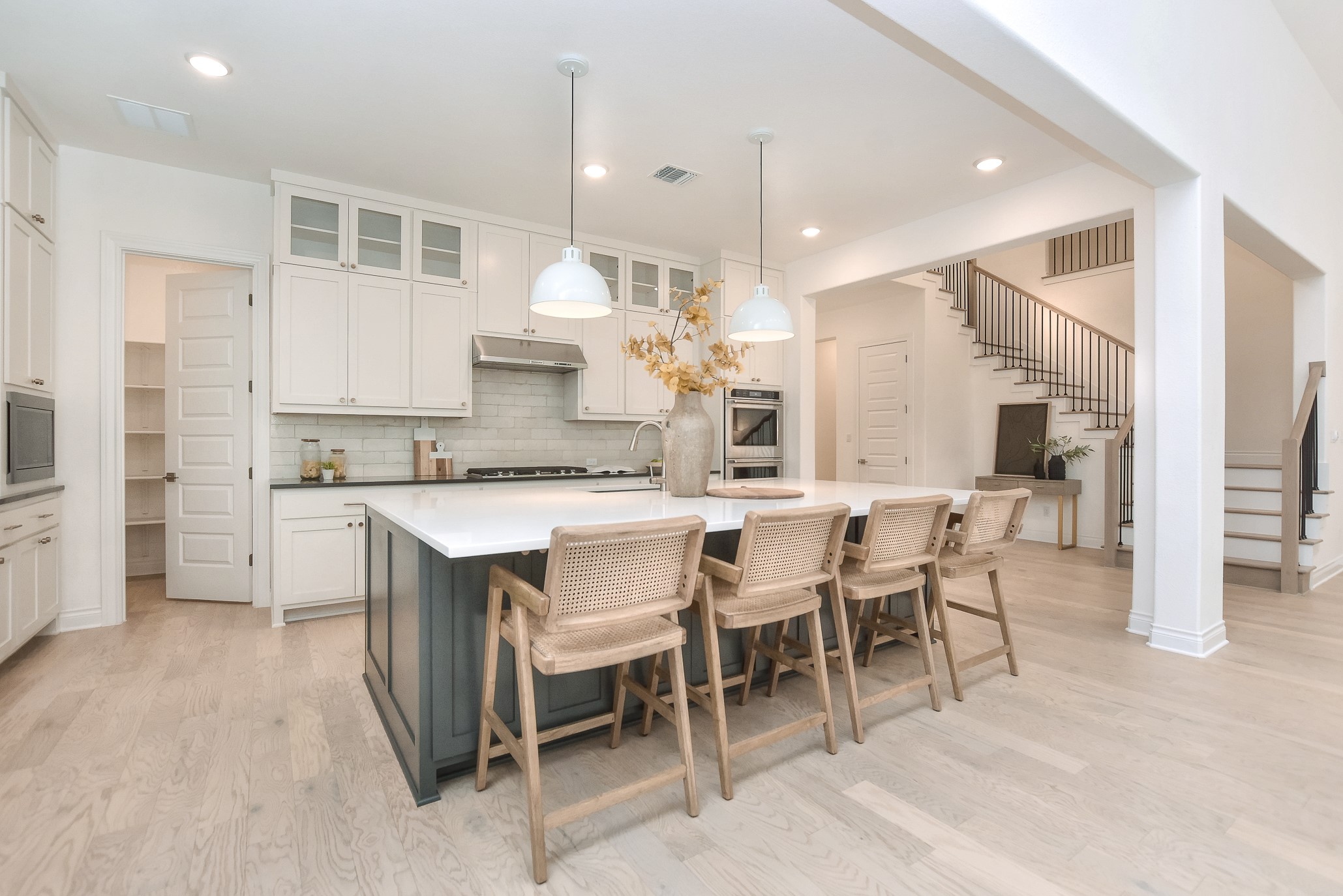 309 Wolf Rdg Road Georgetown, TX 78628 - Photo 10 of 39 Dual tone kitchen with a breakfast bar, dual tone cabinetry, glass fronted cabinets, decorative light fixtures, and an island with sink