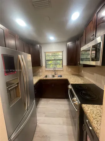 a kitchen with stainless steel appliances granite countertop a refrigerator a stove a sink and a microwave