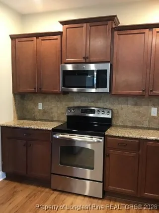 a kitchen with granite countertop wooden cabinets and stainless steel appliances