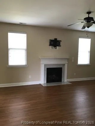 an empty room with wooden floor a fireplace and windows