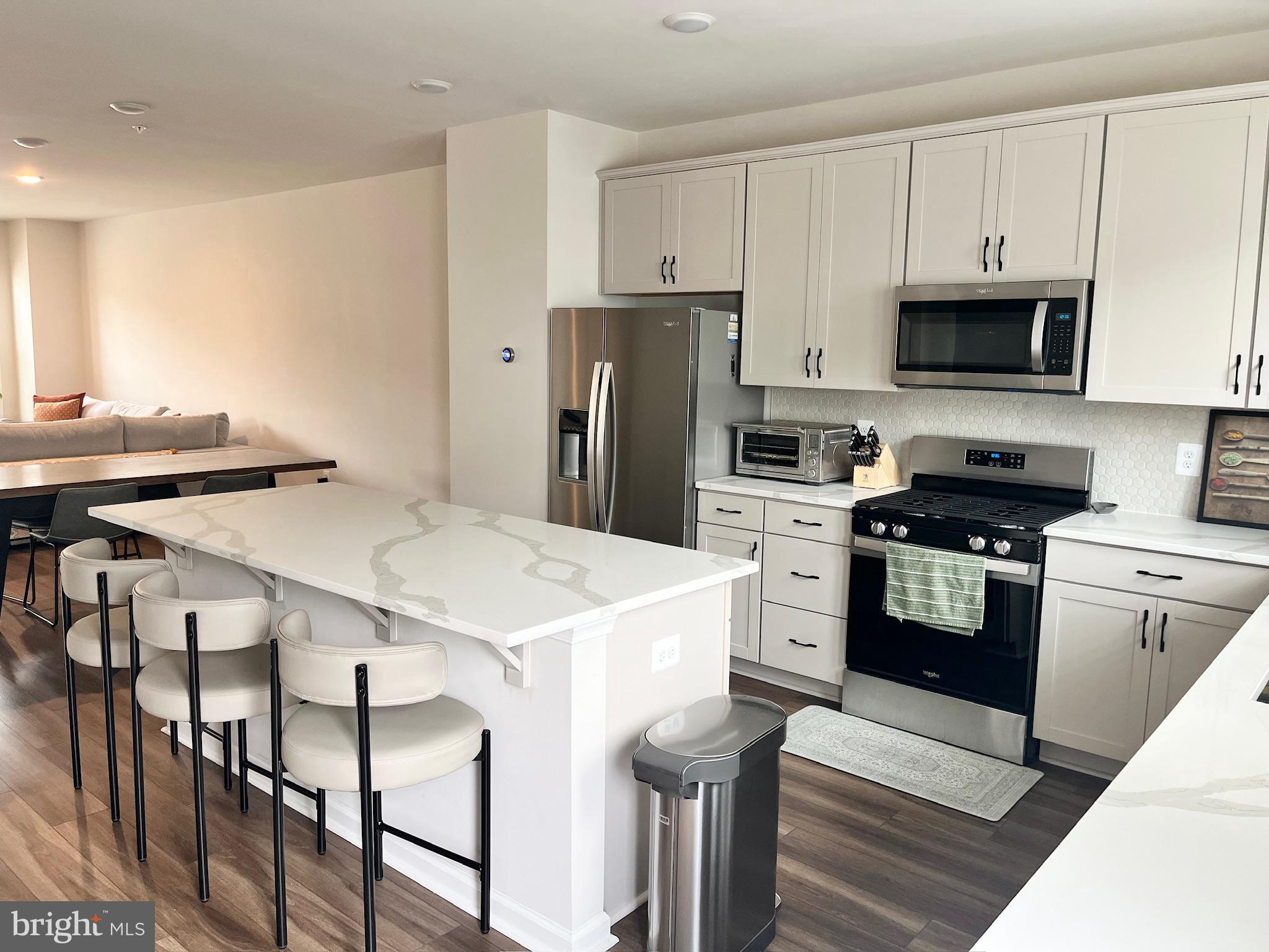 236 Mainstream Drive Laurel, MD 20724 - Photo 17 of 52 a kitchen with stainless steel appliances kitchen island a table chairs and a refrigerator