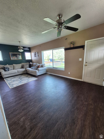 327 North 300 West Logan, UT 84321 - Photo 2 of 12 Living room featuring a textured ceiling, dark wood-type flooring, and ceiling fan