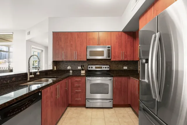 a kitchen with stainless steel appliances granite countertop a stove refrigerator and sink