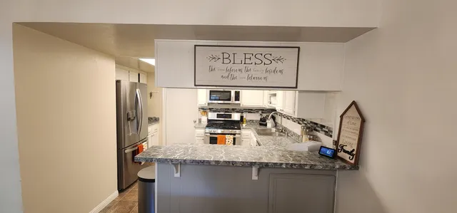a kitchen with stainless steel appliances granite countertop a sink and a refrigerator