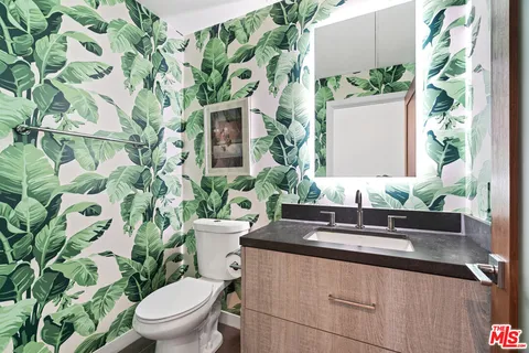 a bathroom with a granite countertop sink and a toilet