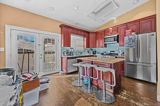 a kitchen with stainless steel appliances granite countertop a refrigerator a sink dishwasher a dining table and chairs with wooden floor