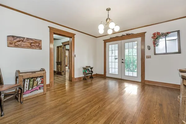 a view of a room with wooden floor chandelier and windows