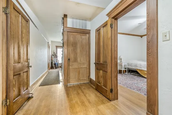 a view of a hallway with wooden floor and a bathroom