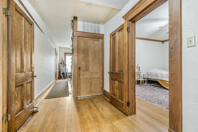 a view of a hallway with wooden floor and a bathroom