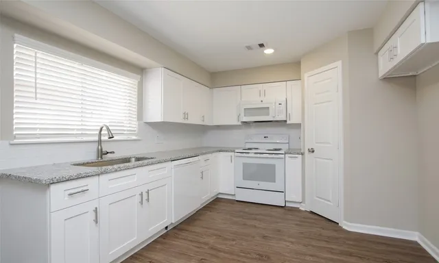 a kitchen with granite countertop white cabinets and white appliances