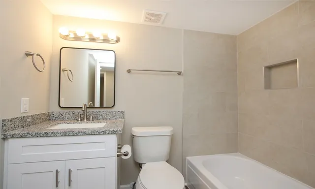 a bathroom with a granite countertop toilet sink and mirror