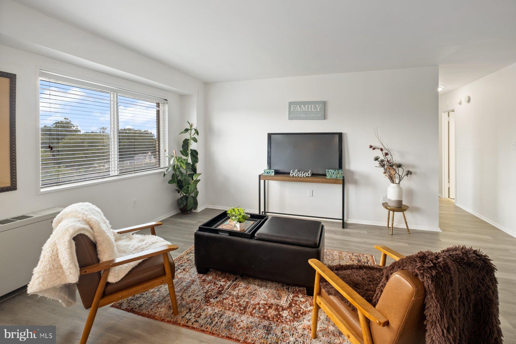 1111 University Boulevard West, Unit 817 Silver Spring, MD 20902 - Photo 9 of 26 a living room with furniture a flat screen tv and a window