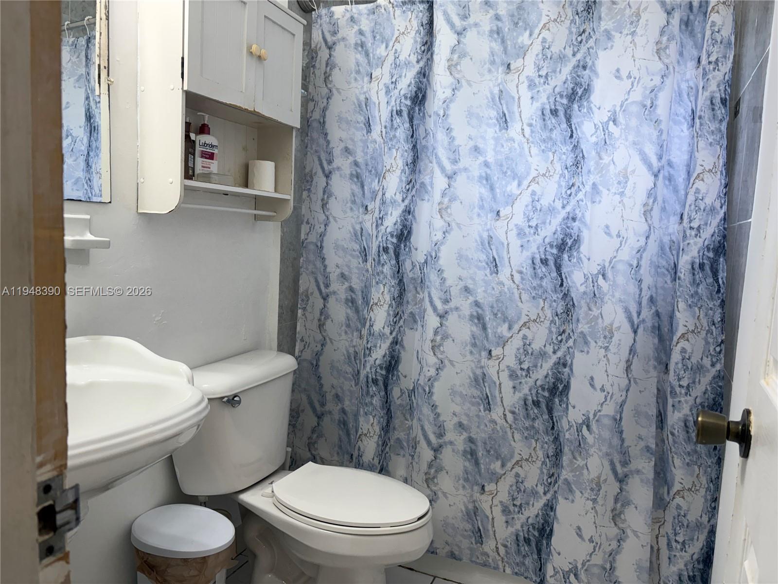 330 North 69th Way Hollywood, FL 33024 - Photo 8 of 20 a white toilet sitting next to a shower curtain