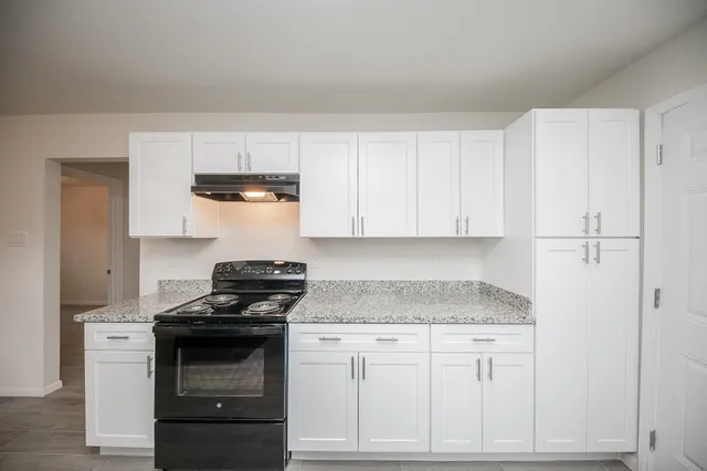 a kitchen with granite countertop white cabinets and stainless steel appliances