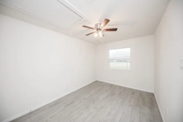 an empty room with a window and ceiling fan
