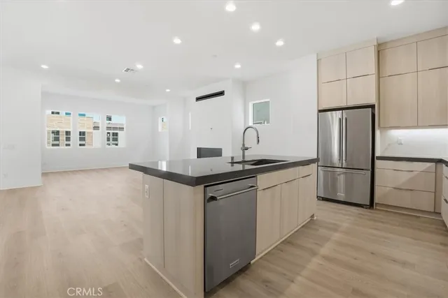 a kitchen with kitchen island granite countertop a sink and a refrigerator