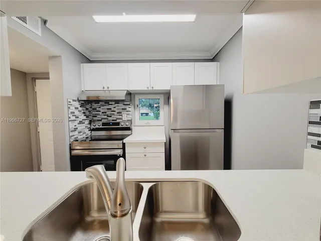 a kitchen with stainless steel appliances a refrigerator and a stove top oven