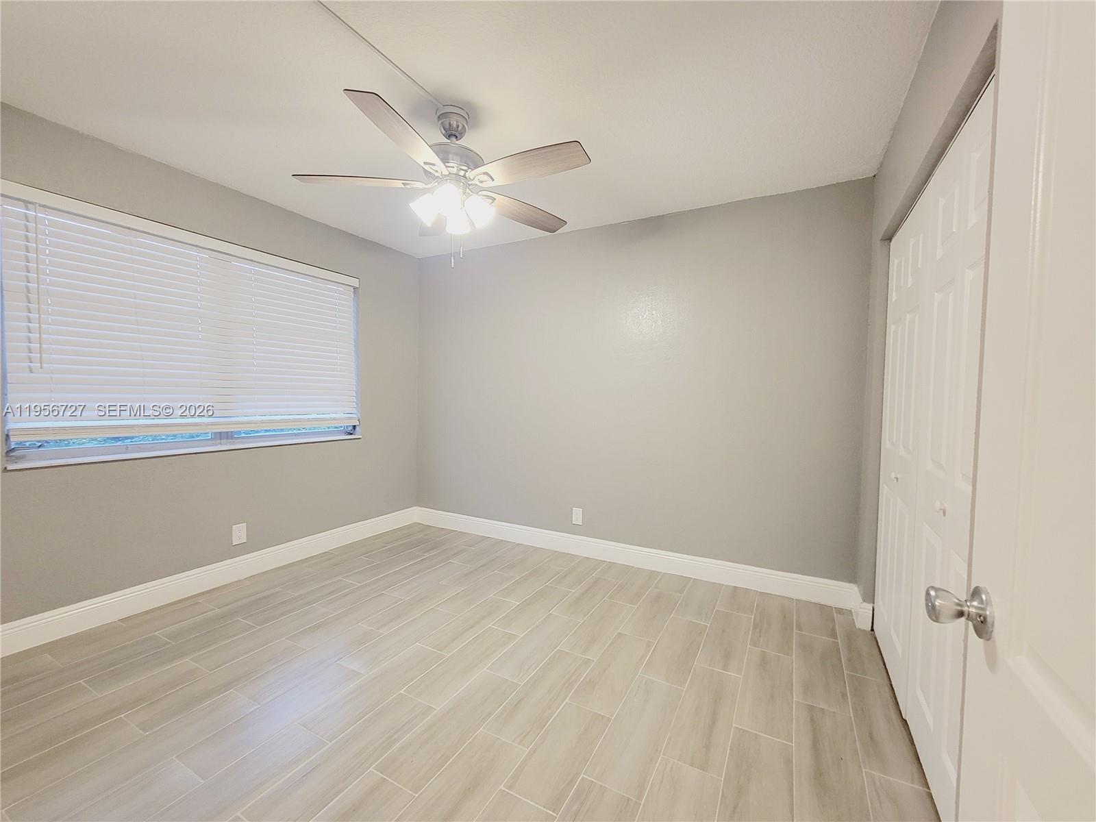 7900 Northwest 50th Street, Unit 108 Lauderhill, FL 33351 - Photo 5 of 18 an empty room with wooden floor fan and windows