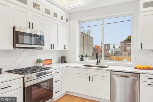 a kitchen with stainless steel appliances white cabinets and a stove top oven