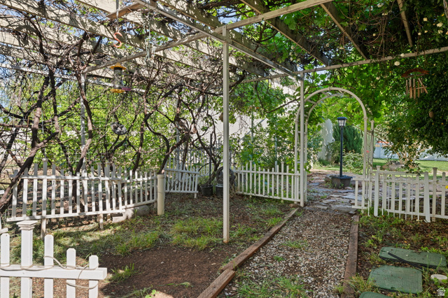 20 Valley Road Leeds, UT 84746 - Photo 41 of 57 Expansive garden area featuring a white metal pergola with mature vines, white picket fencing, and a gravel pathway