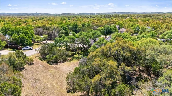 an aerial view of residential house with outdoor space and trees all around