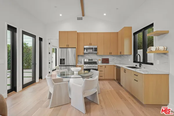 a large kitchen with kitchen island a large counter top space a sink stainless steel appliances and cabinets