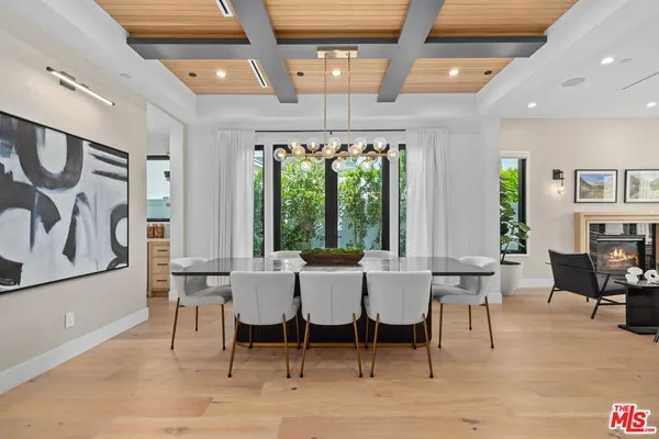a dining room with wooden floor a chandelier a wooden table and chairs