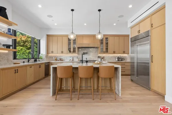 a kitchen with stainless steel appliances kitchen island granite countertop a table chairs sink and cabinets