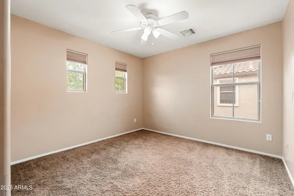 an empty room with windows and ceiling fan