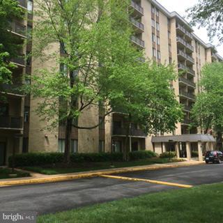 3100 South Manchester Street, Unit 727 Falls Church, VA 22044 - Photo 21 of 23 a view of a tall white building in front of a yard with plants and large trees