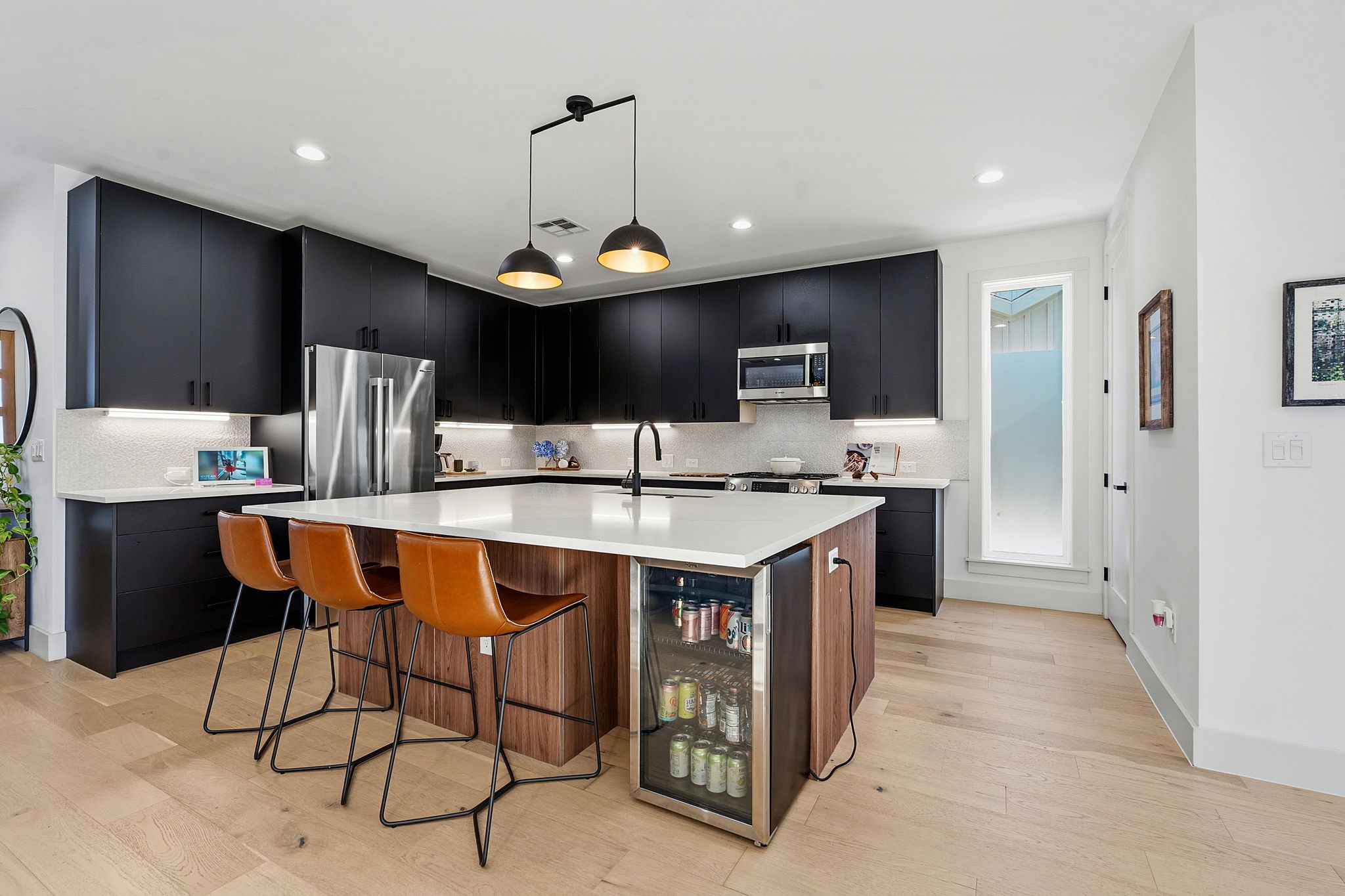 4313 Jinx Avenue, Unit 1 Austin, TX 78704 - Photo 8 of 40 Kitchen featuring dark cabinetry, a breakfast bar, a center island with sink, light wood-style flooring, and stainless steel appliances
