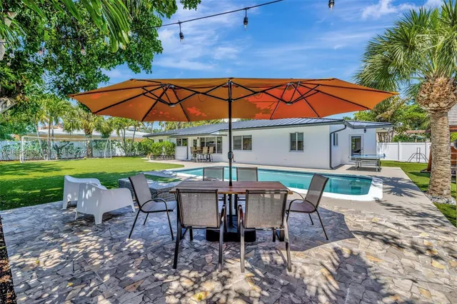 a view of a yard with a table and chairs under an umbrella