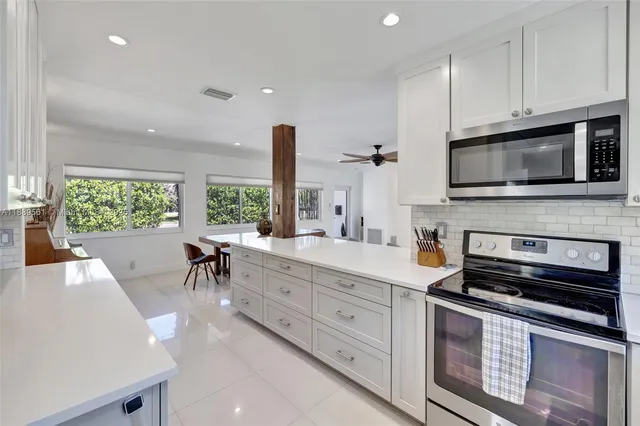 a kitchen with white cabinets appliances a sink and a window