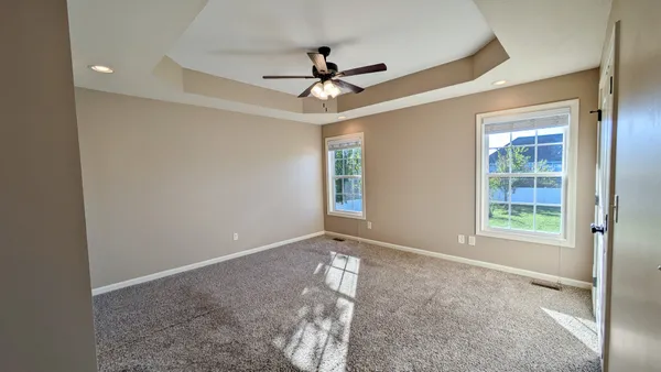 an empty room with windows and ceiling fan