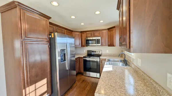 a kitchen with granite countertop stainless steel appliances a refrigerator a stove top oven and sink