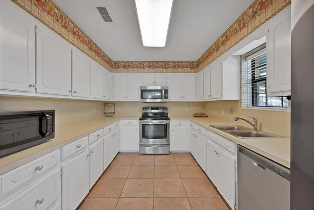 a kitchen with granite countertop a sink dishwasher stove and cabinets