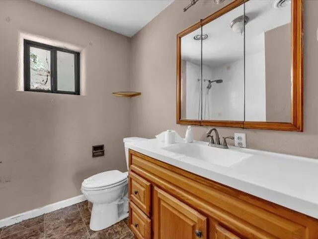 a bathroom with a granite countertop toilet sink and mirror