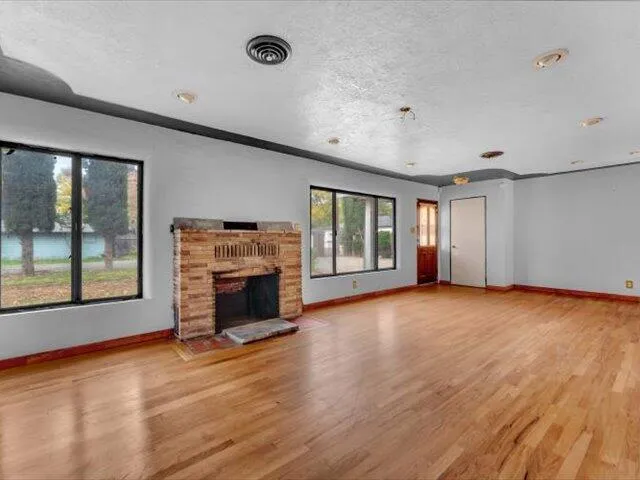 an empty room with windows and fireplace