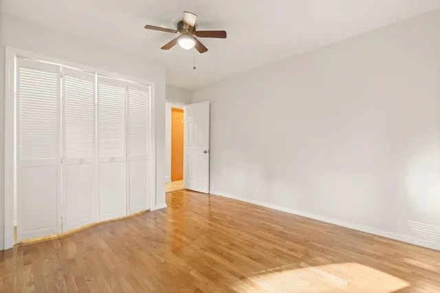 a view of empty room with wooden floor and ceiling fan