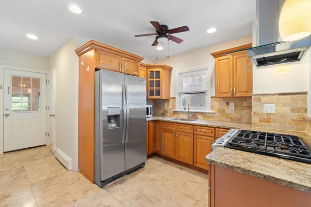a kitchen with stainless steel appliances granite countertop a refrigerator a sink a stove and a refrigerator