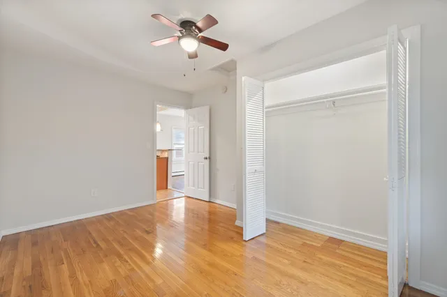 a view of empty room with wooden floor and fan