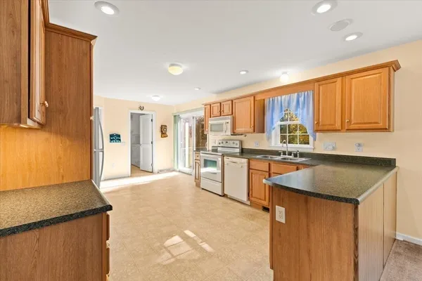 a kitchen with stainless steel appliances granite countertop a stove a sink dishwasher and a refrigerator with wooden floor