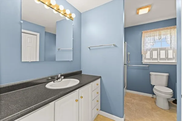 a bathroom with a sink toilet a mirror and a window